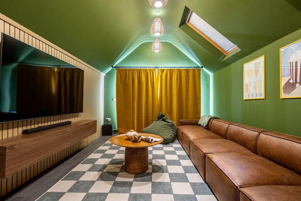 Cinema room with large TV screen mounted to the wall and a large brown sofa