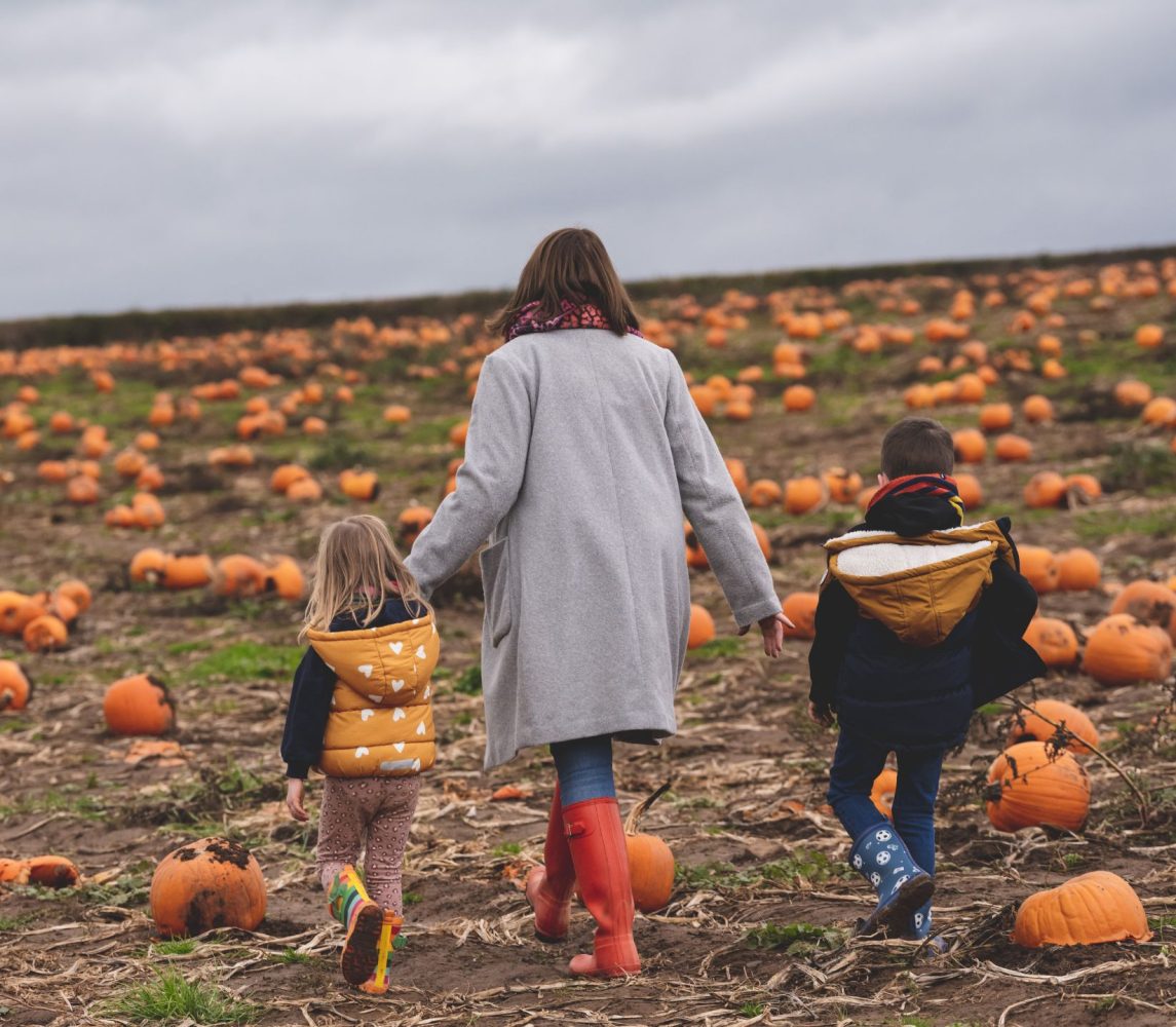 mother and son and daughter walking through a pumpkin patch