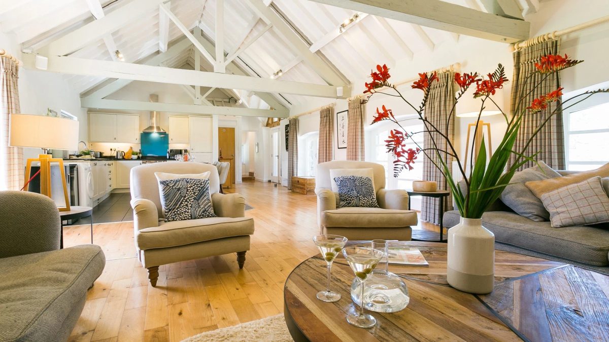 Ty Siam living room with cream armchairs and a coffee table with a vase of red flowers