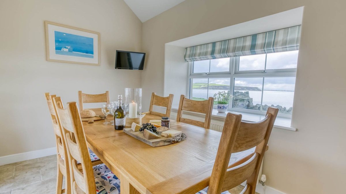 Yr Efail dining table next to a window with views of  the sea. 