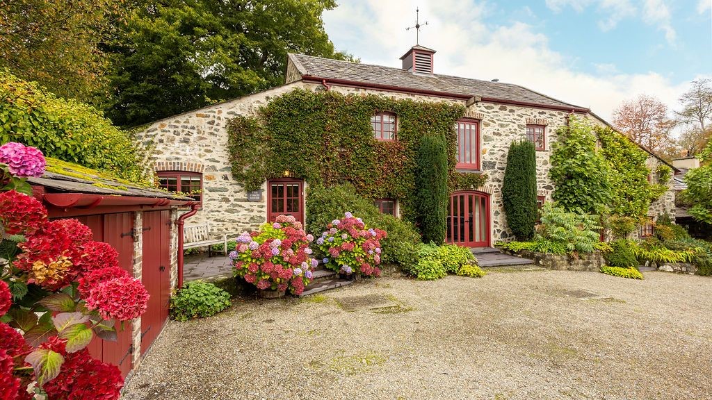 Cadnant Coach House - stone house with red framed windows and moss foliage